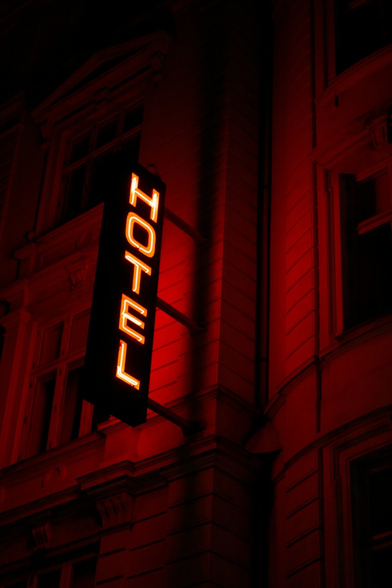 Rótulo de neón con la palabra 'Hotel' iluminado en rojo sobre la fachada de un edificio.